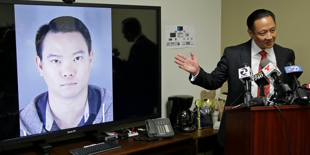 San Francisco Public Defender Jeff Adachi gestures while standing beside a picture of police officer Jason Lai, who resigned earlier in April.