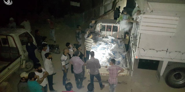 This photo provided by the Syrian anti-government activist group Local Council of Daraya City, which has been authenticated based on its contents and other AP reporting, shows Syrian citizens load food and other supplies from a truck that entered the besieged town of the rebel-held suburb of Daraya, southwest of Damascus, Syria, early Friday, June 10, 2016. The Syrian Arab Red Crescent and the United Nations have delivered food aid to the Damascus suburb of Daraya for the first time since it came under siege in 2012, hours after the U.N. said the Syrian government had approved access to 15 of the 19 besieged areas within Syria. (Local Council of Daraya City via AP)