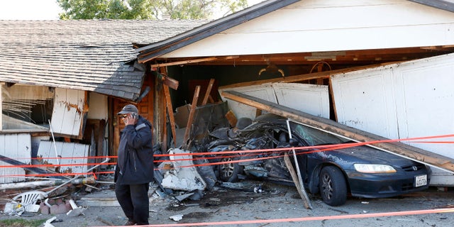 Ray Minter talks on the phone after a truck ran into his home near Interstate 680 in San Jose Tuesday.