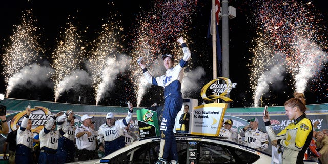 Brad Keselowski stands on his car in Victory Lane after his win in the NASCAR Sprint Cup Series auto race at Kentucky Speedway, Saturday, July 9, 2016 in Sparta, Ky. (AP Photo/Timothy D. Easley)