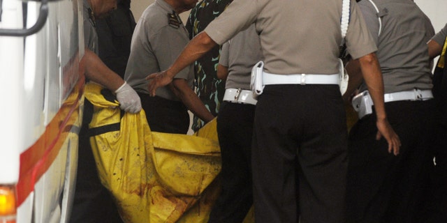 Indonesian police officers arriving at a hospital carry one of the two bodies of militants killed by Indonesian security forces.