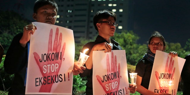 Activists hold posters which read "Jokowi, stop the executions!" during a vigil outside the presidential palace in Jakart. "Jokowi" is the popular nickname of Indonesian President Joko Widodo.