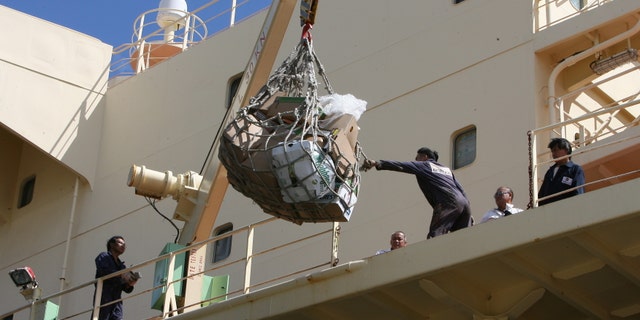 Crew members pull supplies onto the deck of the Newlead Castellano
