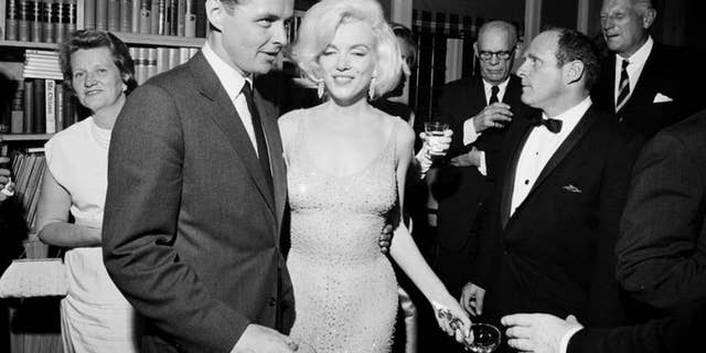 Marilyn Monroe is seen wearing the iconic gown from President Kennedy's birthday fundraiser during a reception in New York City. Standing next to Monroe is Steve Smith, President Kennedy's brother-in-law. This photo is provided by the John F. Kennedy Presidential Library and Museum.