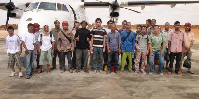 Sailors standing for a group photograph as they prepare to board an airplane after a Somali pirate said they were released.