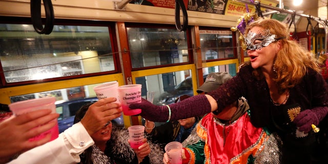 Members of the "Societe des Champs Elysee" toast as they ride the Rampart-St. Claude street car line, which just opened last fall, to commemorate the official start of Mardi Gras season, in New Orleans.