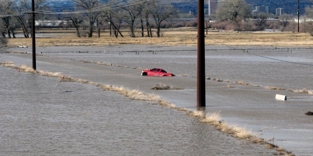 A red pickup truck sits abandoned it after it got stuck in floodwaters at a University of Nevada, Reno, research farm bordering the Truckee River.