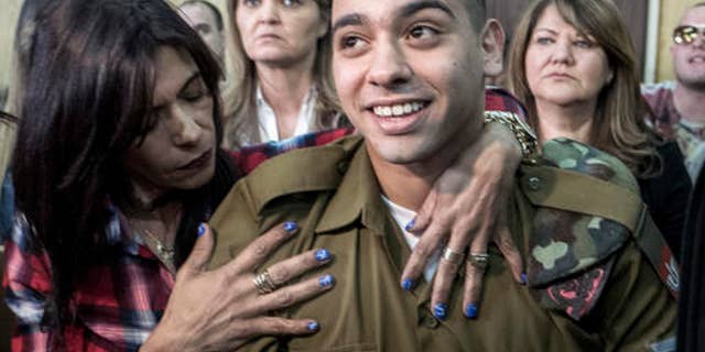 Elor Azaria embraced by his mother at the start of his sentencing hearing.