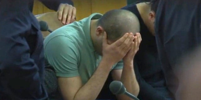 A defendant covers his face at the beginning of the trial.