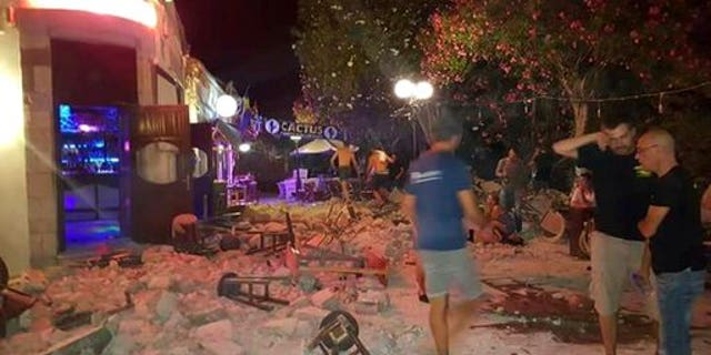 A man lies on the ground as other tourists stand outside a bar after an earthquake on the Greek island of Kos early Friday, July 21, 2017.