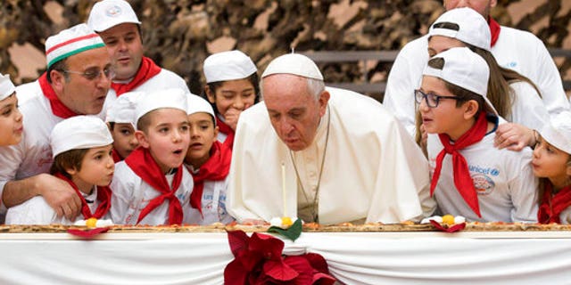 Pope Francis blows out a candle on pizza to celebrate his 81st birthday during a private audience with children at the Vatican.