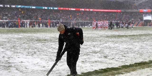 A worker clears snow from field lines at Soldier Field during an NFL game between the Chicago Bears and Cleveland Browns in Chicago on Sunday.