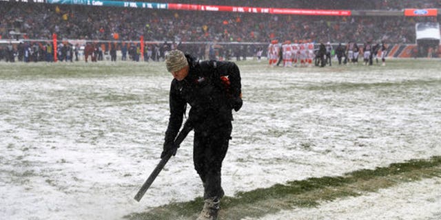 A worker clears snow from field lines at Soldier Field during an NFL game between the Chicago Bears and Cleveland Browns in Chicago on Sunday.