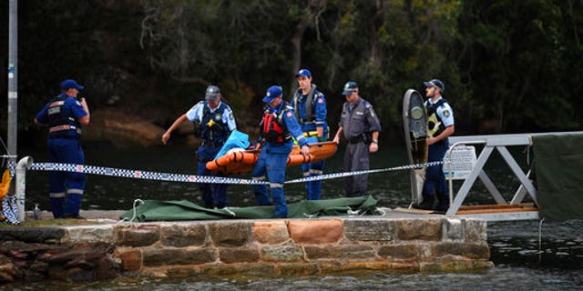 Emergency workers carry to shore what is believed to be a body and debris from a seaplane that crashed into the Hawkesbury River, north of Sydney, Australia.