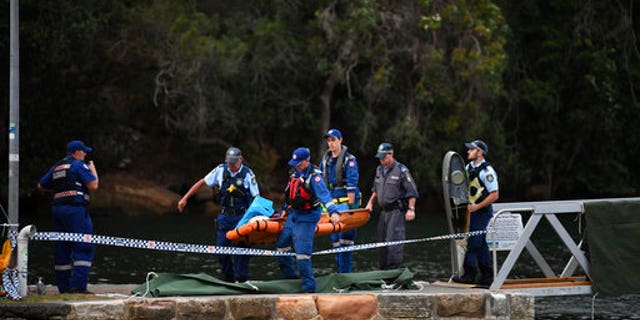 Emergency workers carry to shore what is believed to be a body and debris from a seaplane that crashed into the Hawkesbury River, north of Sydney, Australia.