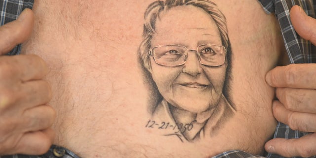 Arthur Burch shows a portrait of his wife's face tattooed on his chest.