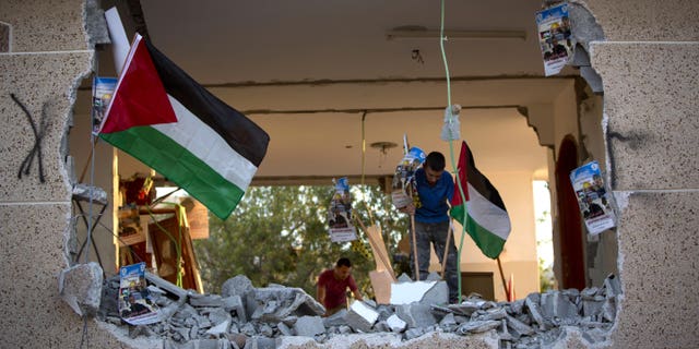 Palestinians place national flags and party banners in what was left of Bashar Masalha's house.