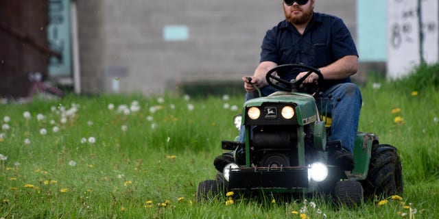 In this photo taken Wednesday May 11, 2016, Detroit Mower Gang member Nick Myer, of Clinton Township, Mich., drives his lawnmower blindfolded during a blindfolded mower contest at Hammerberg Field on Detroit's west side. The volunteers helping to maintain Detroit parks and playgrounds took a crack at mowing grass while blindfolded as part of a friendly competition. (Steve Perez/Detroit News via AP)  DETROIT FREE PRESS OUT; HUFFINGTON POST OUT; MANDATORY CREDIT
