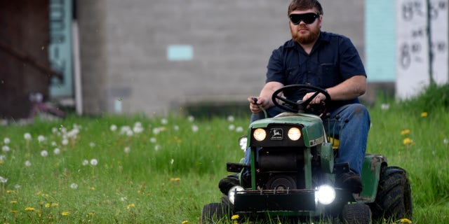 In this photo taken Wednesday May 11, 2016, Detroit Mower Gang member Nick Myer, of Clinton Township, Mich., drives his lawnmower blindfolded during a blindfolded mower contest at Hammerberg Field on Detroit's west side. The volunteers helping to maintain Detroit parks and playgrounds took a crack at mowing grass while blindfolded as part of a friendly competition. (Steve Perez/Detroit News via AP) DETROIT FREE PRESS OUT; HUFFINGTON POST OUT; MANDATORY CREDIT