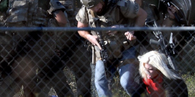 Police officers escort Kristin Bauer after the hostage-taking.