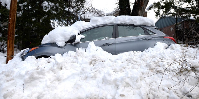 A car sits buried in snow from the blizzard on 9th Street in Boulder, Colo. on Thursday.