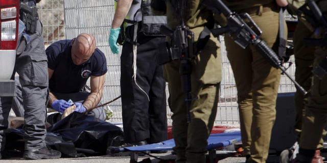 Israeli police officer examines the body of Palestinian attacker Naim Safi.