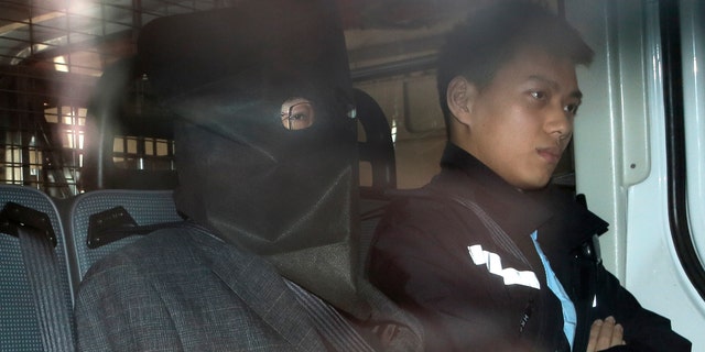 Shi Deyun, left, escorted by a police officer in a police van, arrives at a magistrate court in Hong Kong in January.