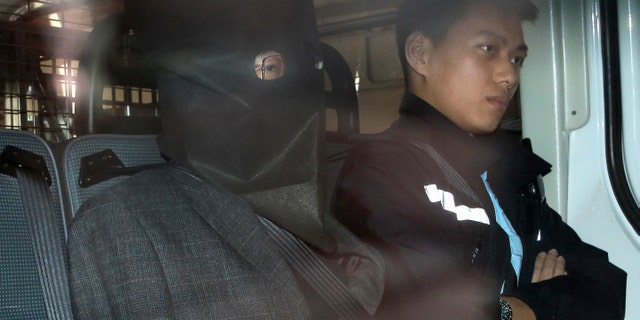 Shi Deyun, left, escorted by a police officer in a police van, arrives at a magistrate court in Hong Kong in January.