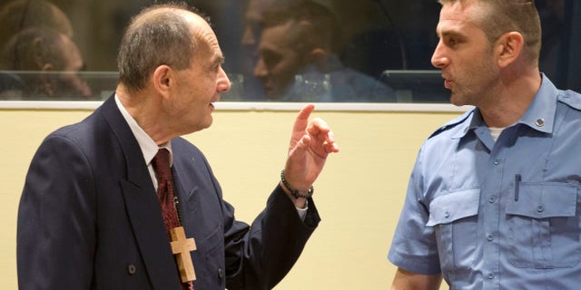 Zdravko Tolimir, left, with a U.N. security guard at the Yugoslav war crimes tribunal in 2015.