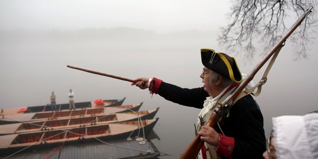 Revolutionary War re-enactor Bill Strunk points his cane towards New Jersey as fog covers the river before the re-enactment of Washington crossing the Delaware River, Friday, Dec. 25, 2015, in Washington Crossing, Pa. (AP Photo/ Joseph Kaczmarek)