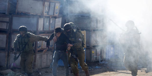 Israeli soldiers arrest a Palestinian protester during clashes in the West Bank village of Kabatiya Thursday.