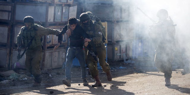 Israeli soldiers arrest a Palestinian protester during clashes in the West Bank village of Kabatiya Thursday.