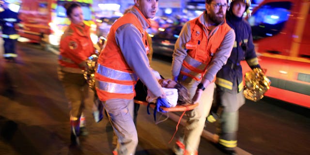 In this Nov. 13, 2015 file photo, a woman is evacuated from the Bataclan concert hall after a shooting in Paris. (AP Photo/Thibault Camus, File)