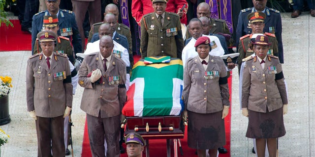 A military honor guard carries anti-apartheid activist Winnie Madikizela-Mandela's coffin, wrapped in the flag of South Africa, out of Orlando stadium following her funeral service, in Soweto, South Africa, Saturday, April 14, 2018.