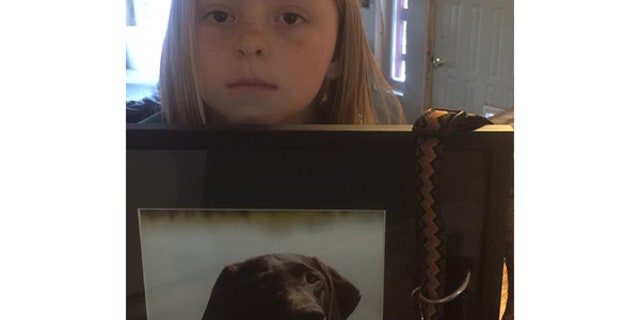 Helfrieck's 8-year-old daughter holds a photo of the family's dog, Abby, killed March 12 by an M-44 in Wyoming.