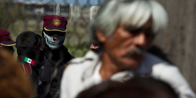 A state police officer wearing a face mask stands behind the fence as relatives of inmates wait for news after a prison riot at Apodaca correctional state facility in Apodaca on the outskirts of Monterrey, Mexico, on Sunday. (AP Photo/Hand Maximo Musielik)