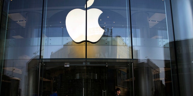 FILE - In this April 1, 2013 photo, a man leaves an Apple store with an iPhone and an iPad in his hands in central Beijing, China. Apple is orchestrating a $3.2 billion acquisition of Beats Electronics, the headphone maker and music streaming distributor founded by hip-hop star Dr. Dre and record producer Jimmy Iovine, according to a Financial Times report published late Thursday, May 8, 2014. (AP Photo/Alexander F. Yuan)