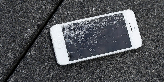 FILE - This Aug. 26, 2015 photo shows an Apple iPhone with a cracked screen after a drop test from the DropBot, a robot used to measure the sustainability of a phone to dropping, at the offices of SquareTrade in San Francisco. Apple for the first time is accepting banged up iPhones as a trade-in from those wanting to upgrade. (AP Photo/Ben Margot)