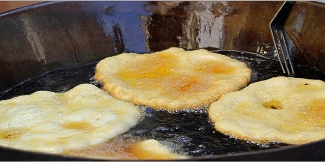 tasty Fried Apple fritters in the cauldron of boiling oil on sale at the market