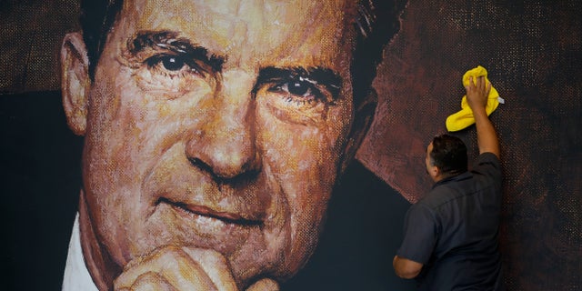 FILE -- In this Wednesday, Oct. 5, 2016 photo, Tayron Santos cleans the newly-installed wall mural of former President Richard Nixon in the lobby area of the Richard Nixon Presidential Library and Museum in Yorba Linda, Calif.