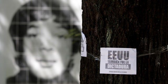 March 16, 2016: A picture of a person that was disappeared during Argentina's military dictatorship is seen behind a leaflet on a tree that reads in Spanish "The U.S. was also the dictatorship, Obama out of former Argentine Navy School of Mechanics" at the Space for Memory and for the Promotion and Defense of Human Rights in Buenos Aires. (AP Photo/Natacha Pisarenko)
