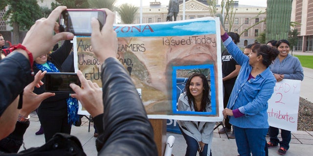 FILE - In this Dec 17, 2014, file photo, Erika Andiola gets her photo taken at the Arizona State Capitol in Phoenix, as thousands of young immigrants moved a step closer to getting driver's licenses in Arizona. A single mother battling cancer and a victim of domestic abuse are among the immigrants who qualify for Arizona driver's licenses but have been illegally denied the chance to drive a car, a group of advocacy organizations said in a new federal lawsuit. Denying licenses to some immigrants in the country illegally who have been granted deferred action, or protection from deportation, is unconstitutional, according to the claim filed Monday, Sept. 12, 2016 by the Mexican American Legal Defense and Educational Fund, the National Immigration Law Center and the Ortega Law Firm.(Nick Oza /The Arizona Republic via AP, File)