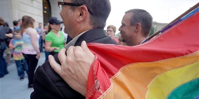 May 12, 2014: Shon DeArmon, right, puts his arm around his partner James Porter while holding a flag outside the Pulaski County Courthouse in Little Rock, Ark.