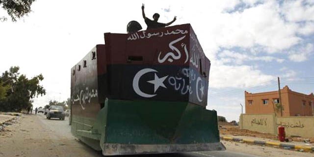 Oct. 19, 2011: An anti-Gaddafi fighter flashes victory signs on an armored bulldozer during violent clashes with pro-Gaddafi forces at the frontline in center Sirte.