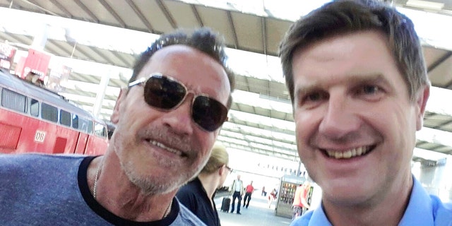 Arnold Schwarzenegger poses with Munich police officer Stefan Schmitt after being stopped for cycling too fast in a Munich train station.