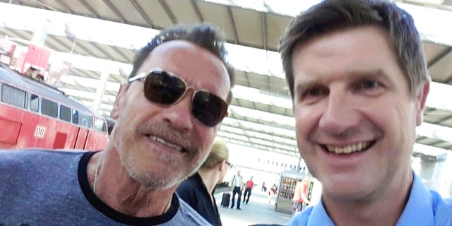 Arnold Schwarzenegger poses with Munich police officer Stefan Schmitt after being stopped for cycling too fast in a Munich train station.