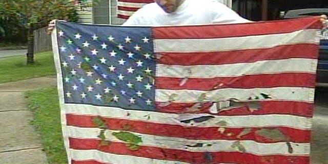 Christian Ashby, of Portland, Ore., holds an American flag that was vandalized outside of his home sometime late Saturday or early Sunday.