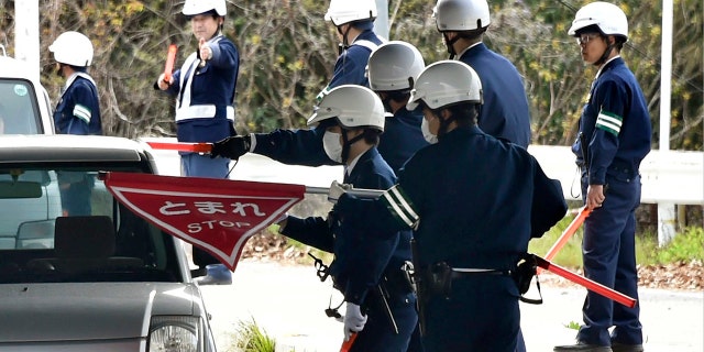In this April 11, 2018, photo, police officers inspect cars at a checkpoint in Onomichi, Hiroshima prefecture.