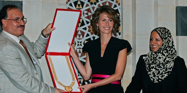 August 27, 2008: Karim Farman, Chairman of Paris-Based Arab Woman Studies Center, left, and member Shakour Al-Ghomari, right, give Syria's first lady Asma Assad the Center's prize of the Arab First Lady of 2008, in Damascus. The prize was awarded to Assad for her role in sponsoring National projects aimed at enhancing education and development in rural areas in Syria.