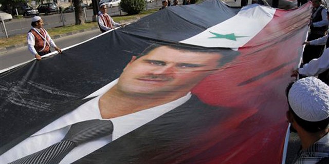 Supporters of Syrian President Bashar Assad carry a huge portrait of Assad as they march during a demonstration in his support in Damascus, Syria, June 8.